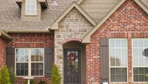 A brick home with a black and glass entry door.